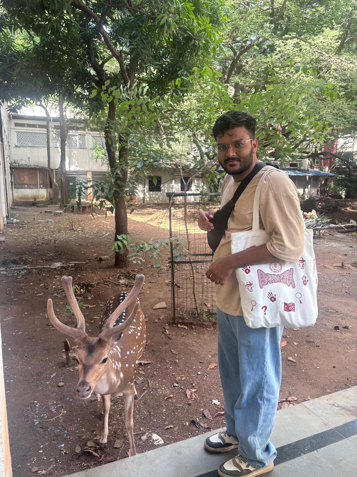 Aman Chandra H with a spotted deer on a tree-lined campus